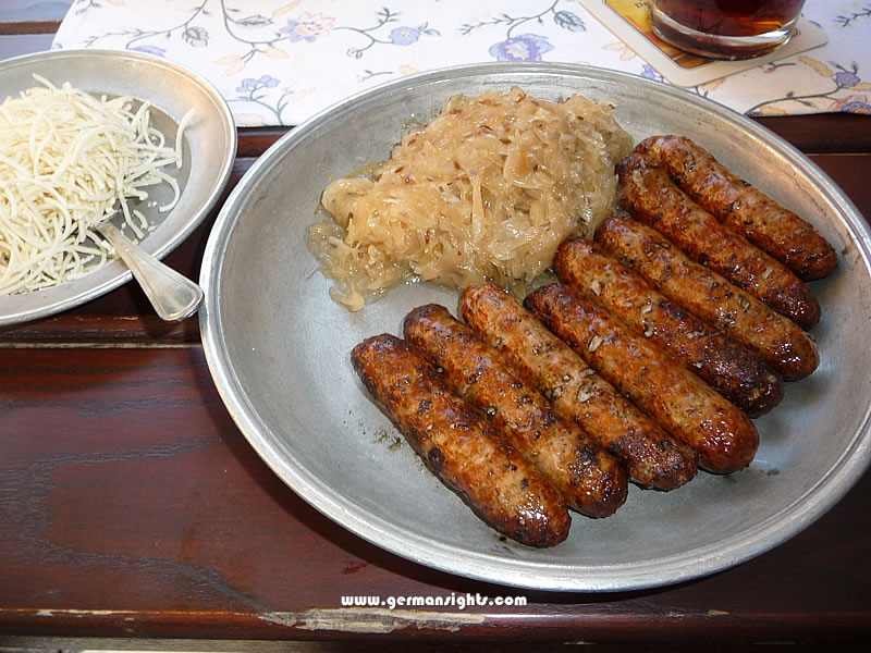 Nuremberg sausages with sauerkraut and horseradish in a traditional pewter plate.